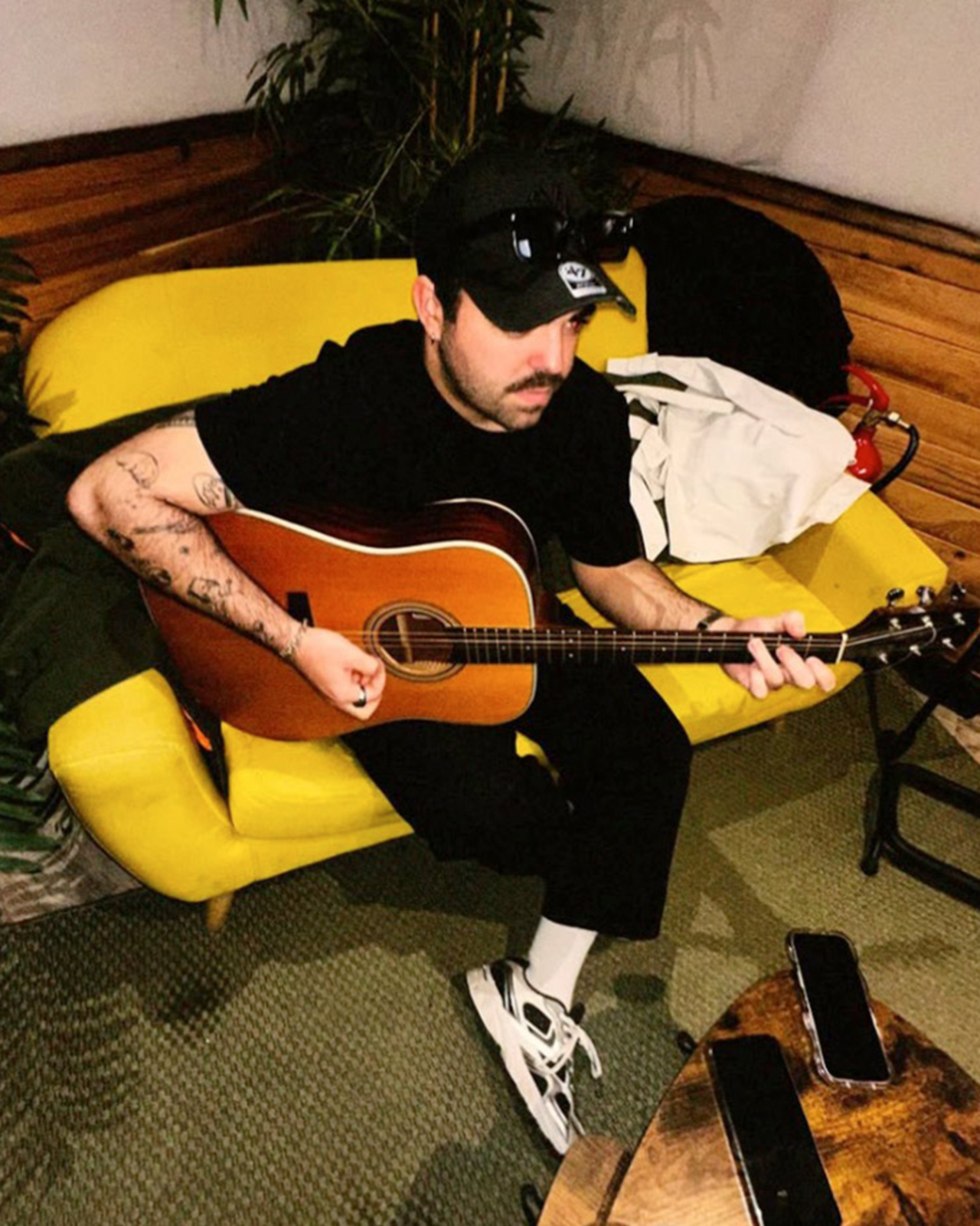 Mingos Lorenzo cunha guitarra acústica sentado nun sofá amarelo